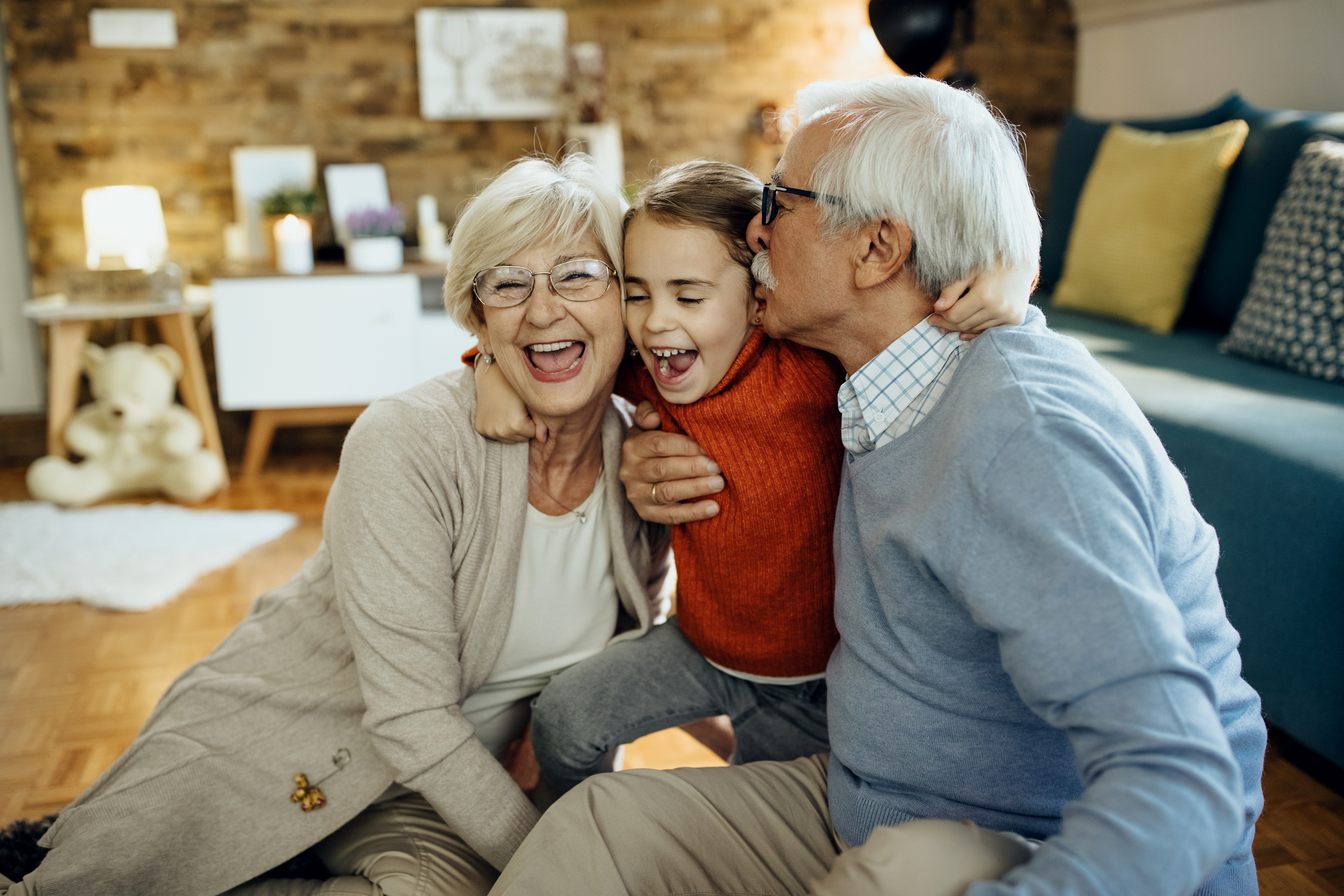 Grandparents laughing with their granddaughter at home
